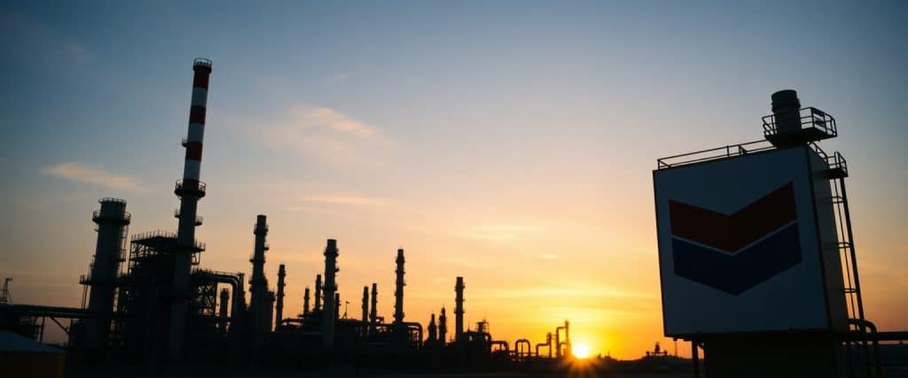 Chevron oil refinery with company logo at sunset, symbolizing energy production