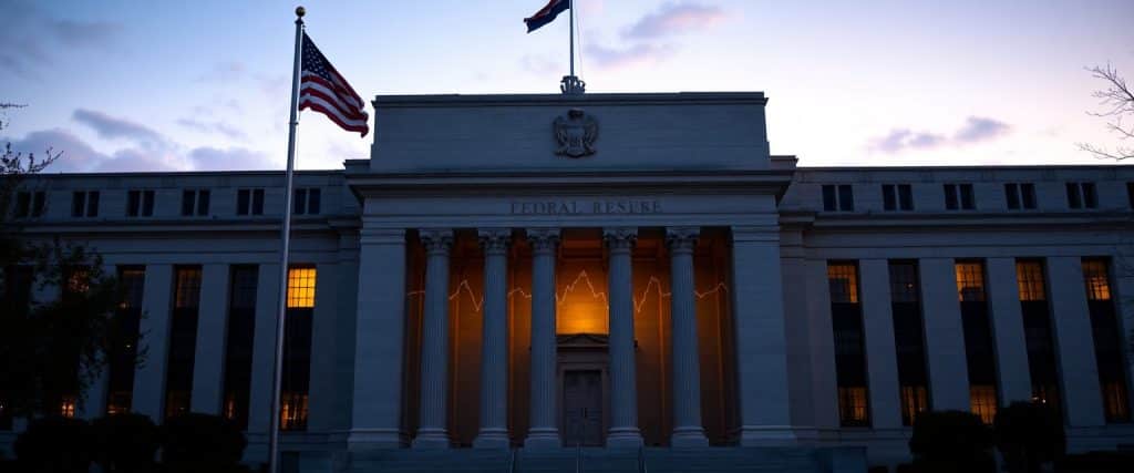 Federal Reserve building with digital graphs of declining interest rates.